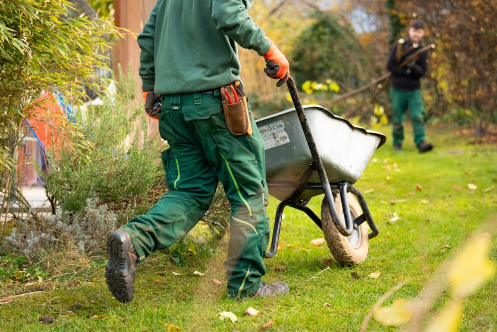 Jardinier professionnel poussant une brouette dans un jardin en entretien