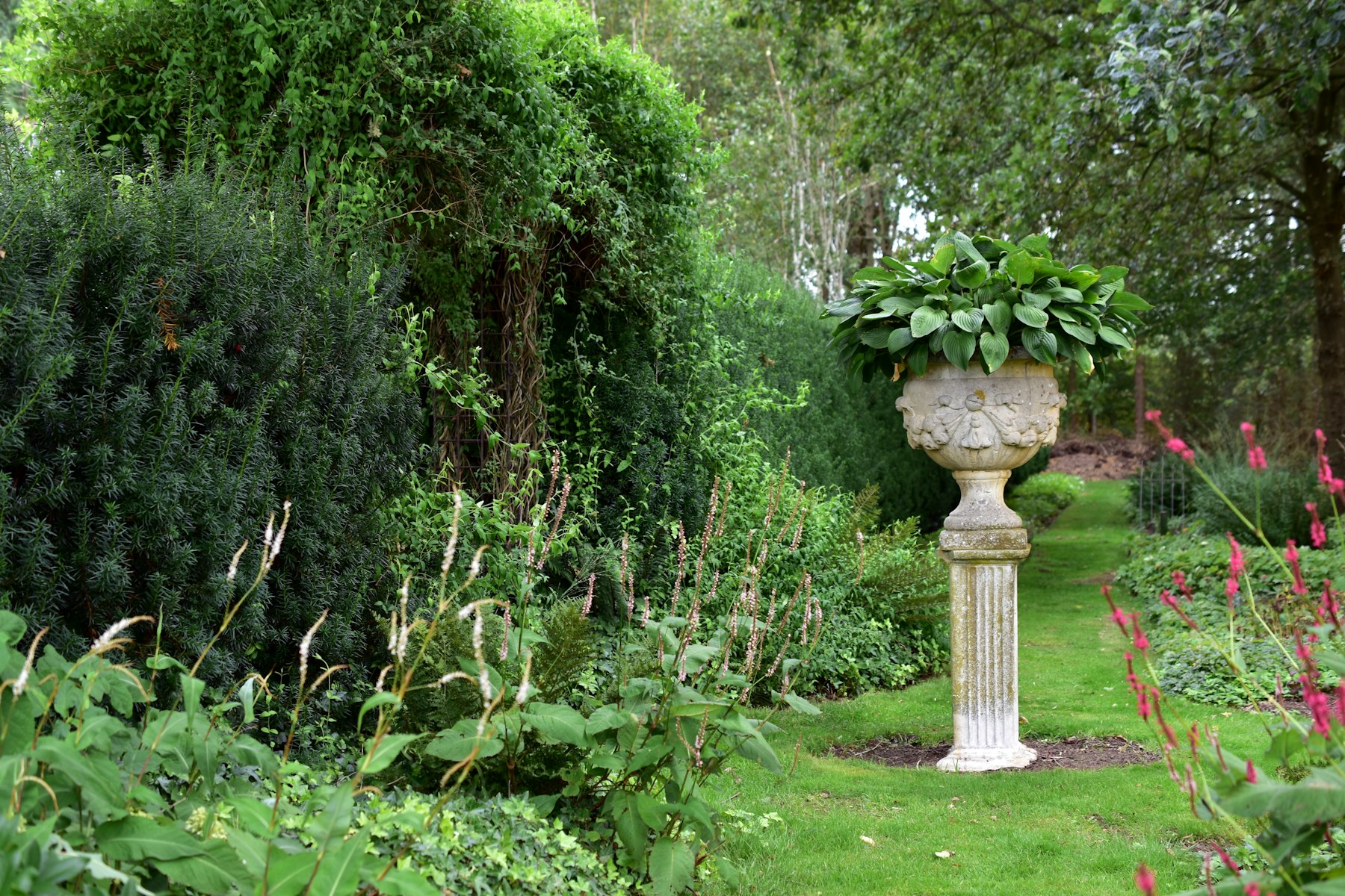 Jardin verdoyant avec massifs et statue